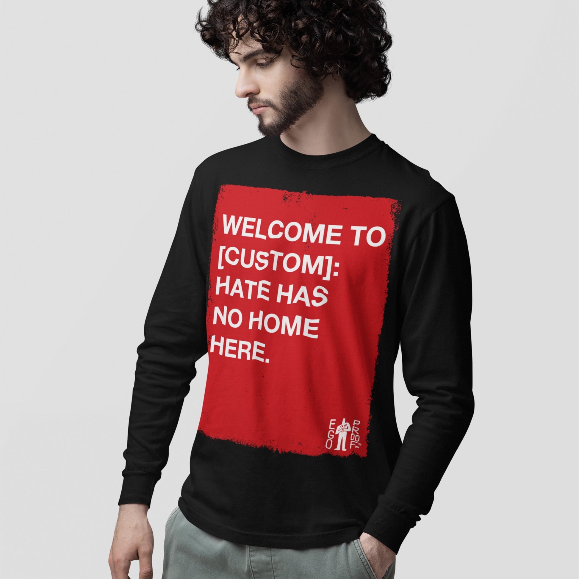 Young man wears the Custom Hate Has No Home Here Long Sleeve T-shirt, featuring a red rectangle with a powerful message against hate and discrimination, embodying activism and community pride.