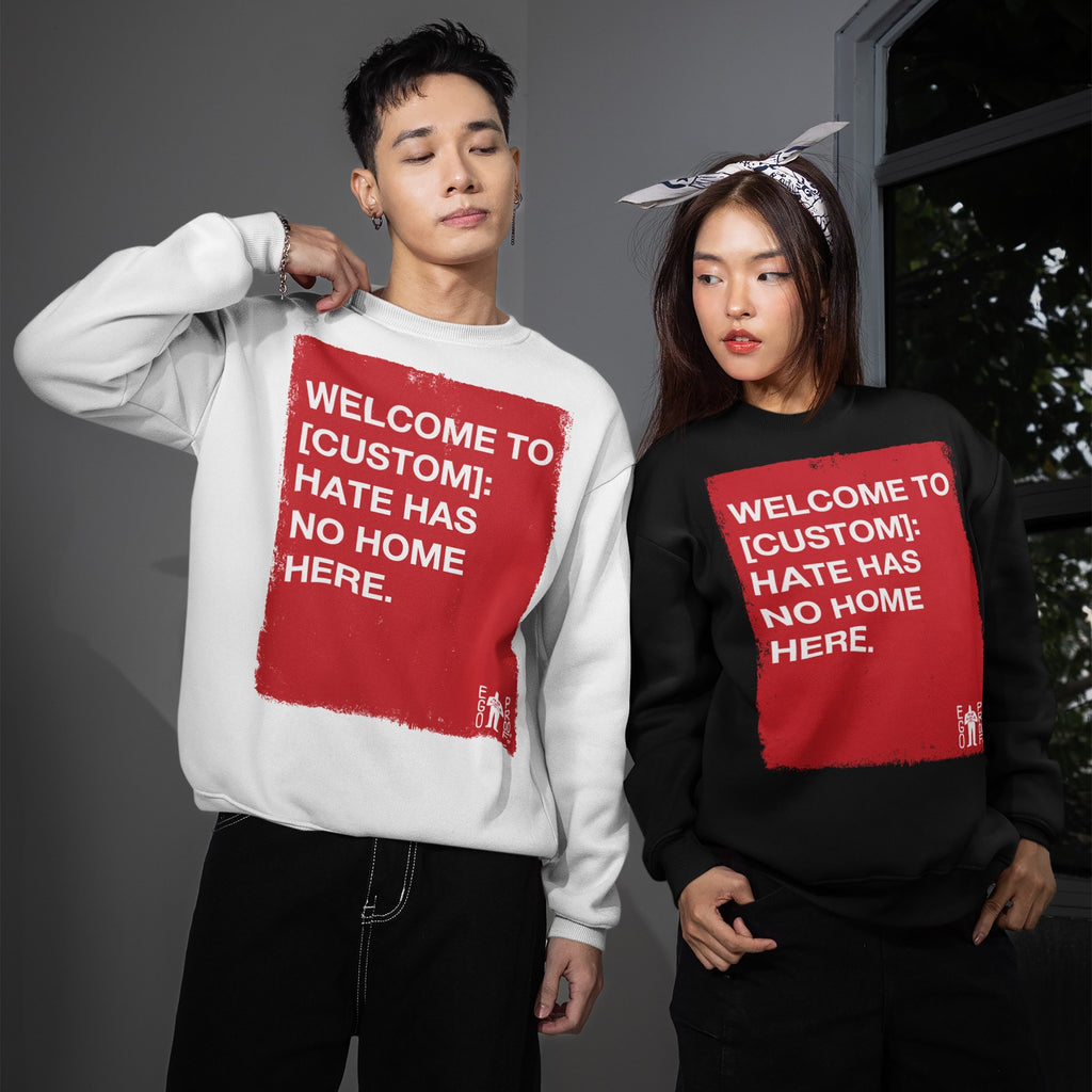 Two young adults model the Custom Hate Has No Home Here Sweatshirt, showcasing bold red text promoting equality. The customizable crewneck champions activism and unity through its impactful message.