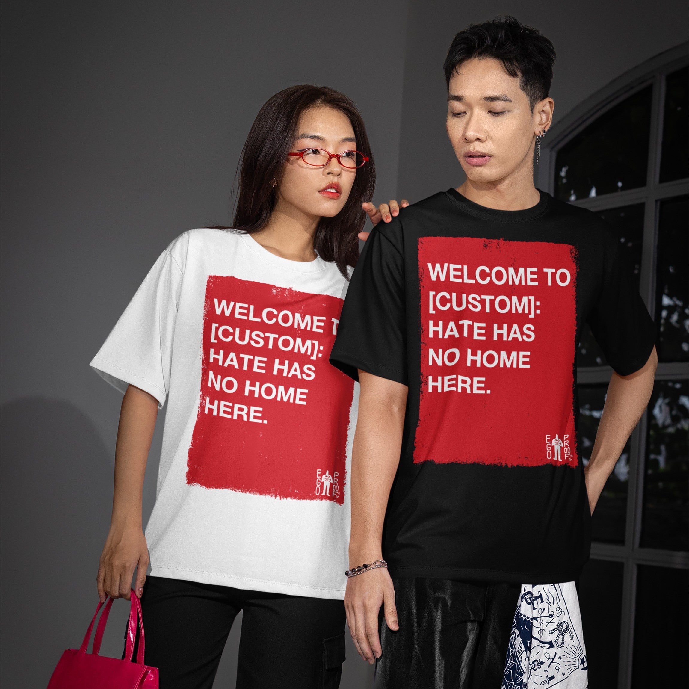 Two young adults model Custom Hate Has No Home Here T-shirts, featuring customizable red graphics promoting inclusivity. Perfect for showcasing justice and equality, aligning with the store's advocacy for change.