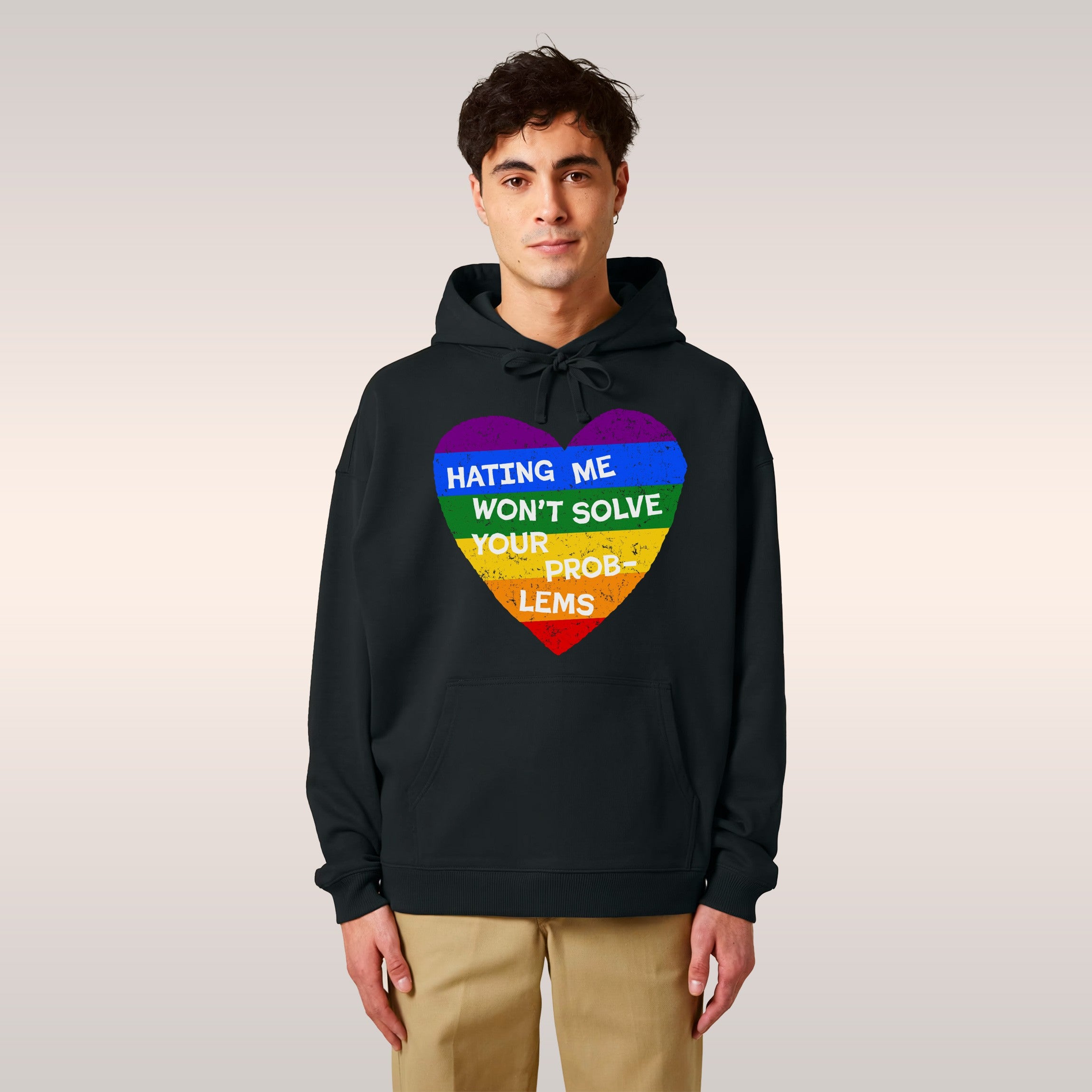 Young person leans against a playground structure wearing a No LGBTQ Hate hoodie featuring a rainbow-striped heart with the m