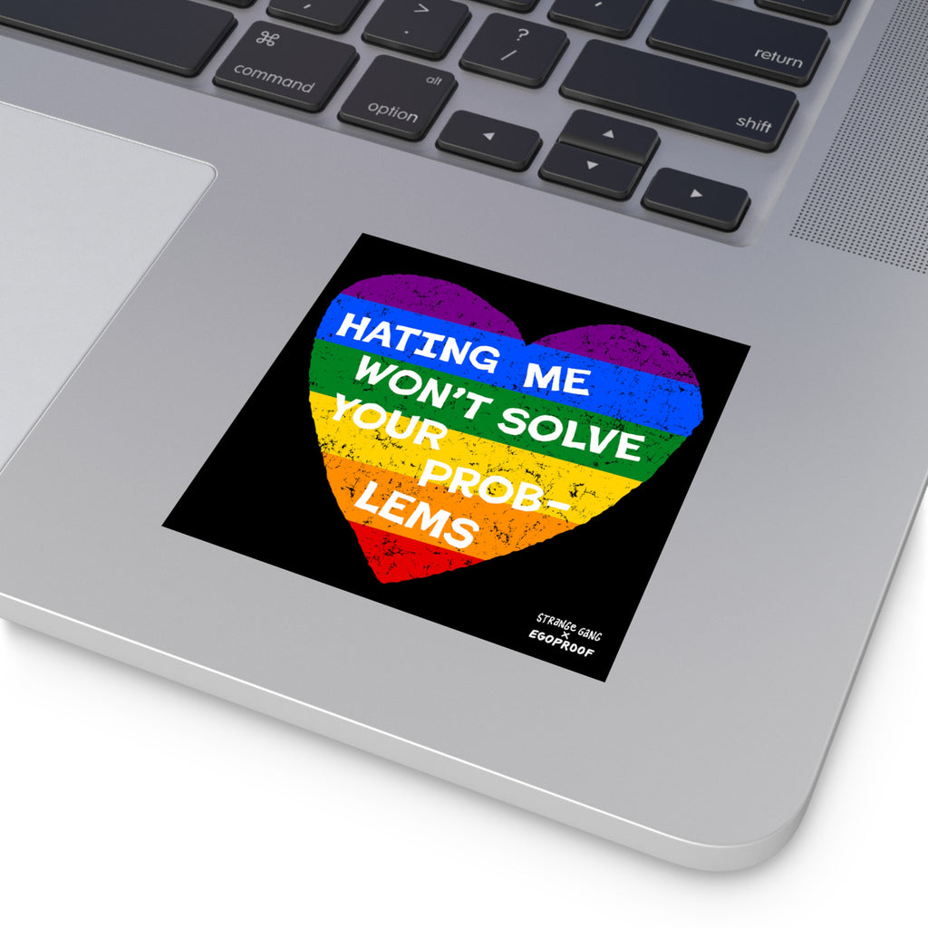 Silver laptop corner with a visible keyboard features a No LGBTQ Hate sticker, showcasing a distressed rainbow heart with Hating Me Won’t Solve Your Problems, highlighting LGBTQ+ allyship and resilience.