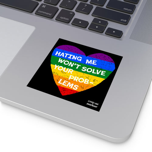 Silver laptop corner with a visible keyboard features a No LGBTQ Hate sticker, showcasing a distressed rainbow heart with Hating Me Won’t Solve Your Problems, highlighting LGBTQ+ allyship and resilience.
