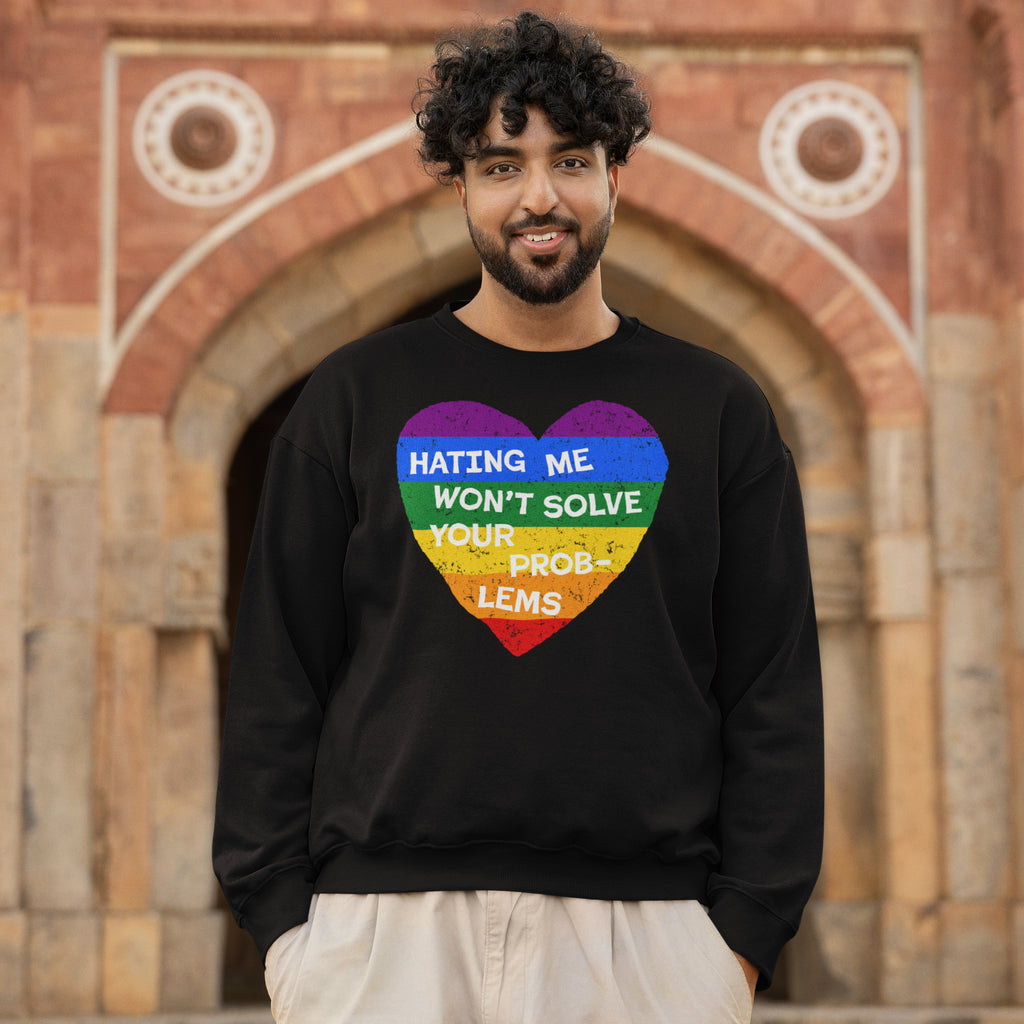 Young man in a black No LGBTQ Hate Shirt with a distressed rainbow heart and slogan, advocating love and resistance, standing confidently in front of a historic stone archway.