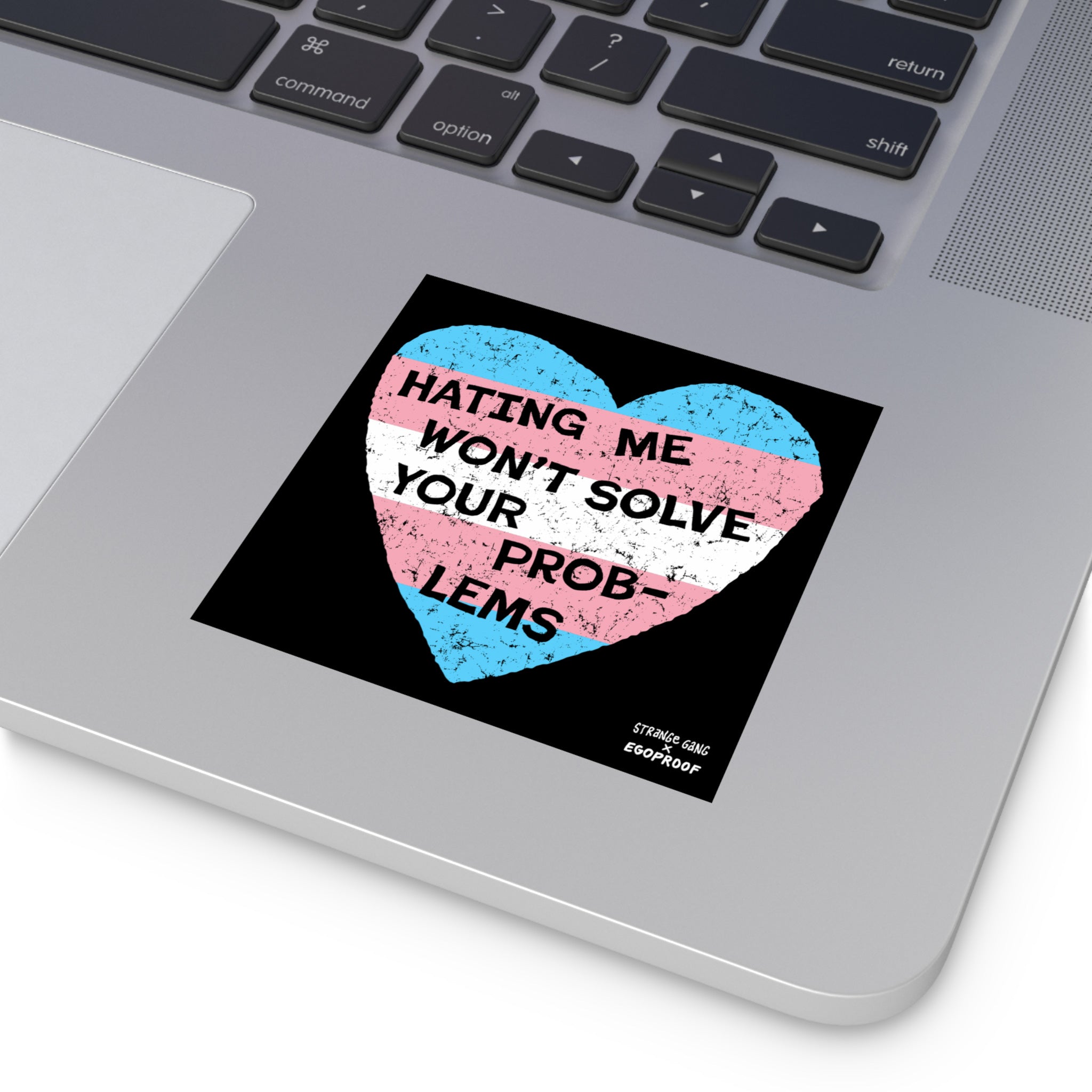 Silver laptop corner showcasing the No Trans Hate Sticker & Magnet, a distressed heart with trans pride colors and the message HATING ME WON’T SOLVE YOUR PROBLEMS, emphasizing trans-affirming identity.