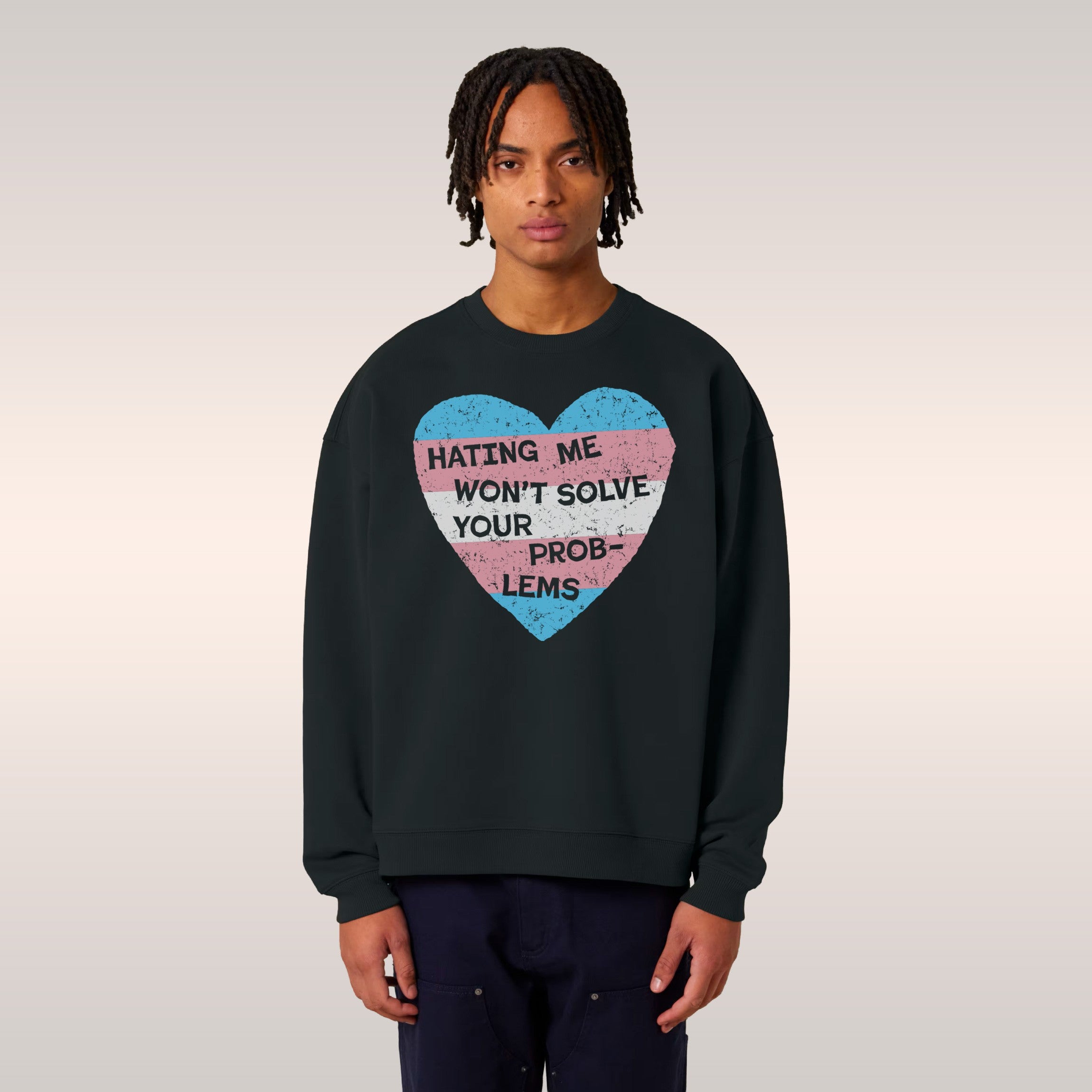 A person wears a black No Trans Hate Shirt featuring a distressed heart with trans flag colors and the slogan HATING ME WON'T