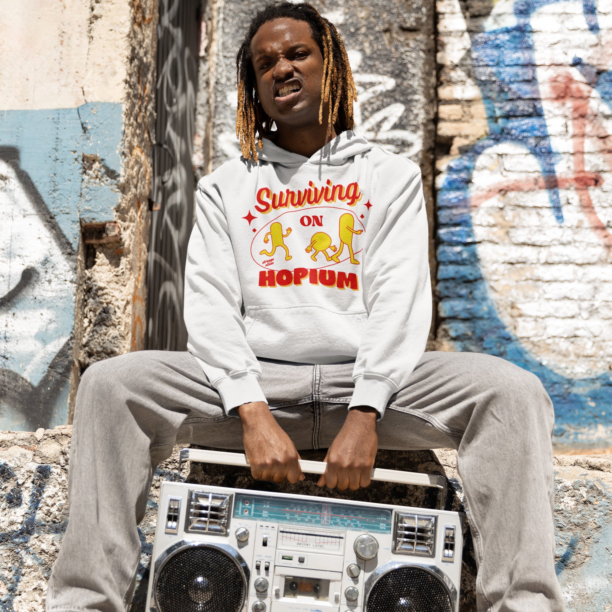 Person in urban scene wears a Surviving on Hopium hoodie, featuring cartoon hops, holding a vintage boombox. A symbol of whimsical optimism and individuality, supporting NAMI.