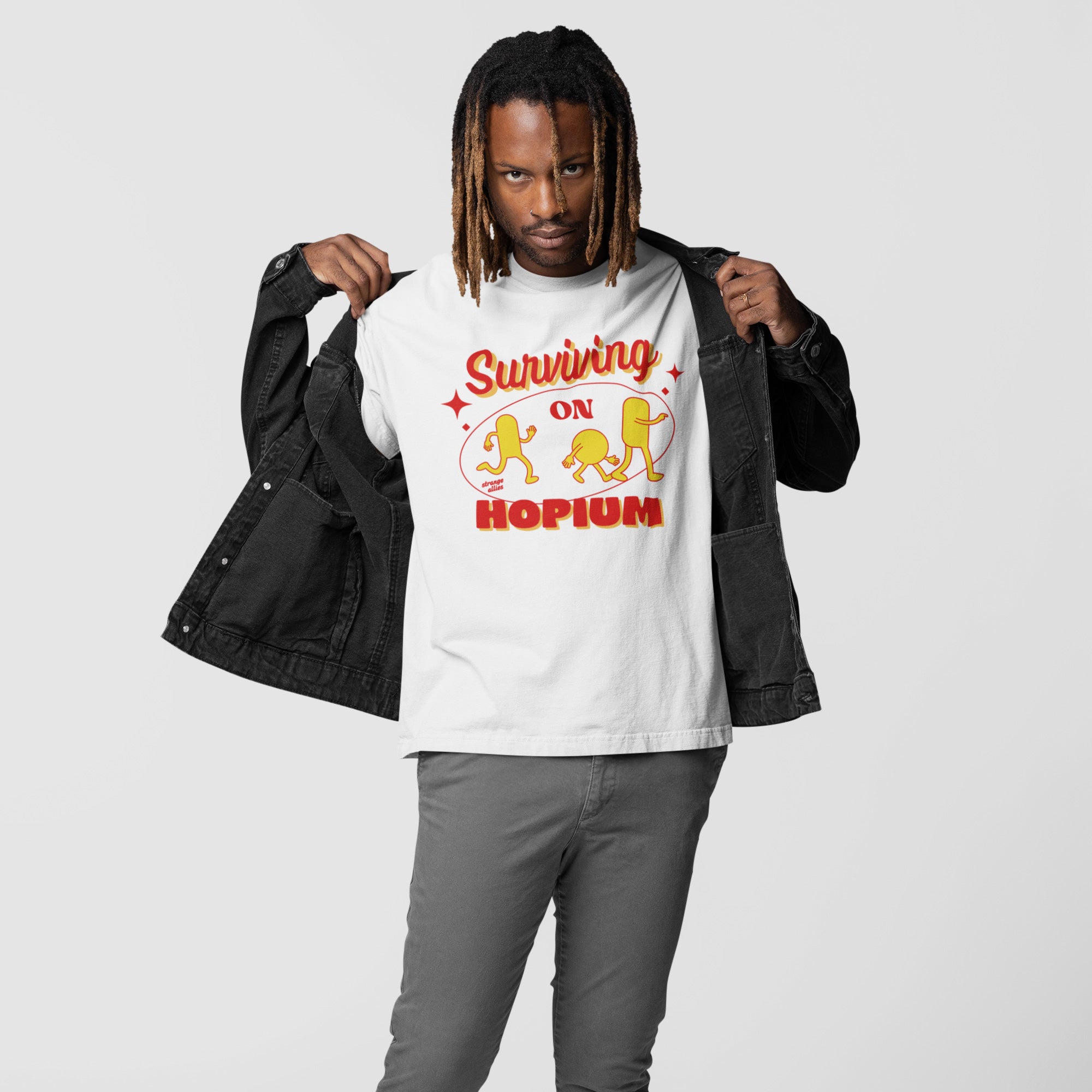 Person wearing a dark jacket opens it to reveal the Hopium Shirt, featuring bold Surviving on Hopium text and stylized cartoon figures, embodying whimsical optimism and supporting mental health causes.