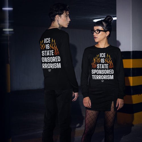 Two people wearing black long-sleeve ICE Is State Sponsored Terrorism shirts with flame graphics, embodying protest and activism in a dim parking garage.