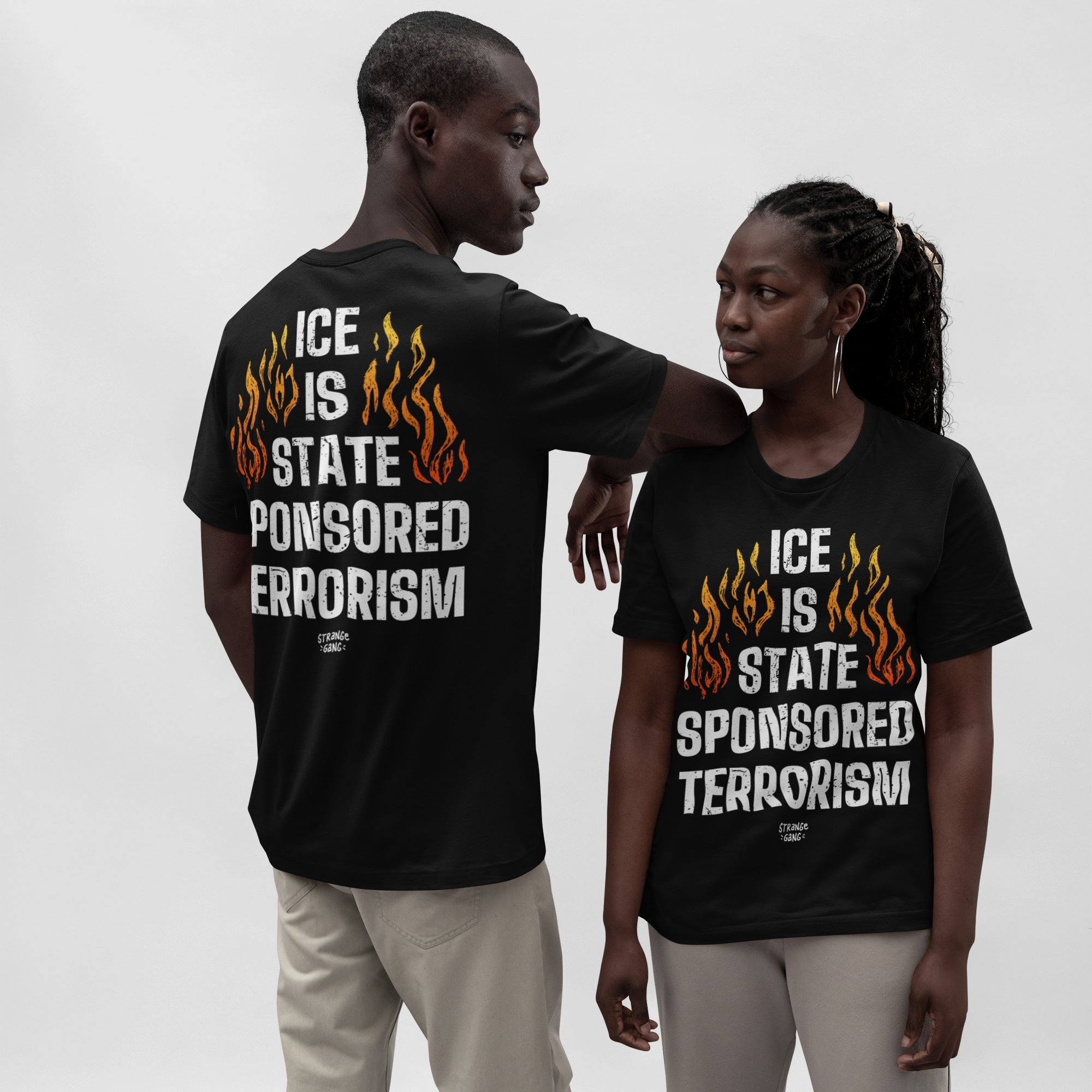 Two individuals wear the ICE Is State Sponsored Terrorism Shirt, displaying the slogan in bold letters and orange flames, highlighting its activist message against a plain background.