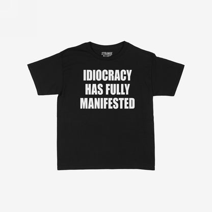 Idiocracy Women's Baby Tee features bold white text IDIOCRACY HAS FULLY MANIFESTED on a black T-shirt, highlighting societal critique with a nod to the cult classic film.