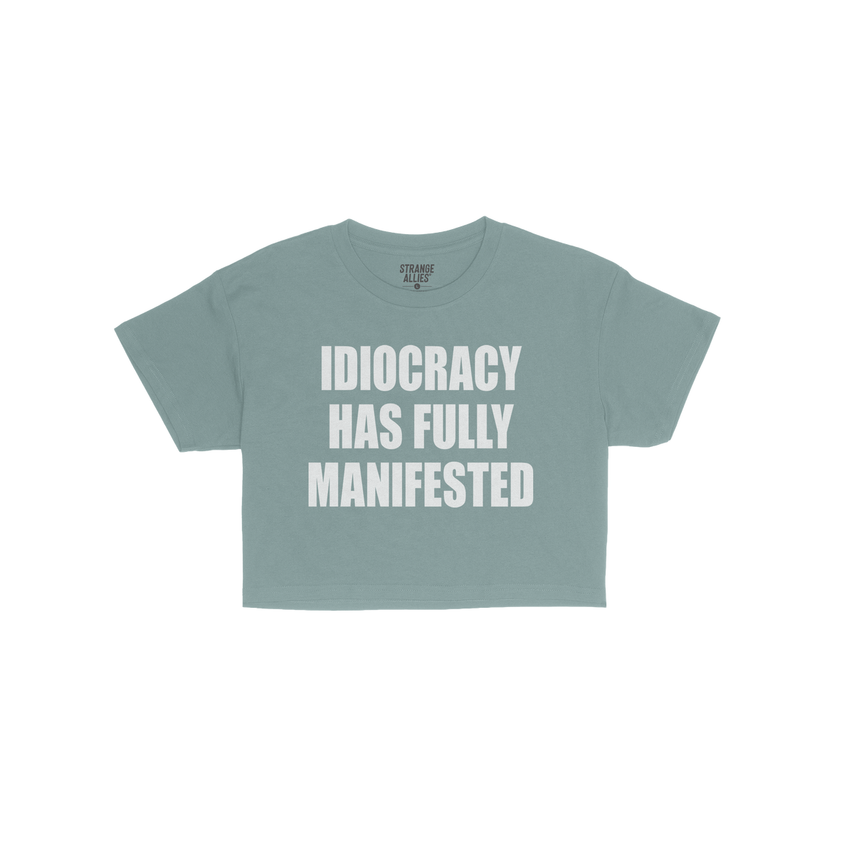 The Idiocracy Women's Baby Tee displays bold white text stating IDIOCRACY HAS FULLY MANIFESTED, capturing a satirical nod to 