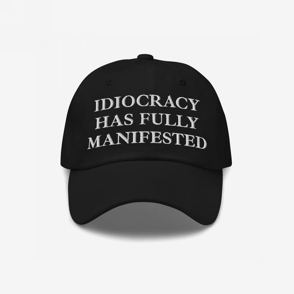 Black baseball-style cap featuring the bold embroidered text IDIOCRACY HAS FULLY MANIFESTED in classic serif type, blending satirical commentary with style, perfect for those who wear their beliefs visibly.