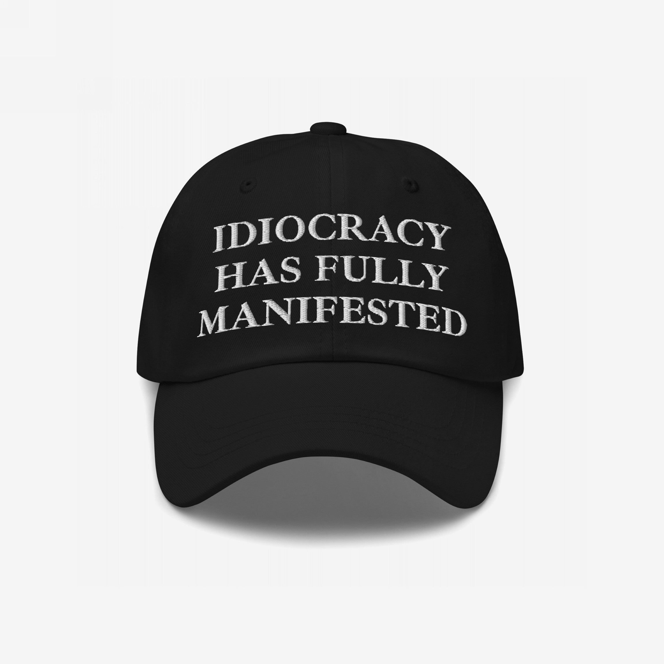 Black baseball-style cap featuring the bold embroidered text IDIOCRACY HAS FULLY MANIFESTED in classic serif type, blending satirical commentary with style, perfect for those who wear their beliefs visibly.