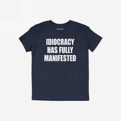 The Idiocracy T-shirt features a bold white slogan declaring “IDIOCRACY HAS FULLY MANIFESTED,” capturing the essence of modern disillusionment and cultural critique.