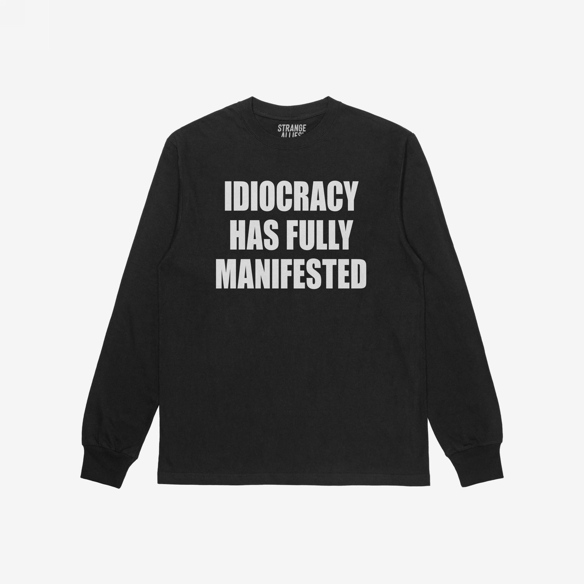 Black long-sleeve Idiocracy T-shirt features bold white text stating, IDIOCRACY HAS FULLY MANIFESTED, embodying a blunt societal critique. The brand label, STRANGE ALLIES, is visible inside.