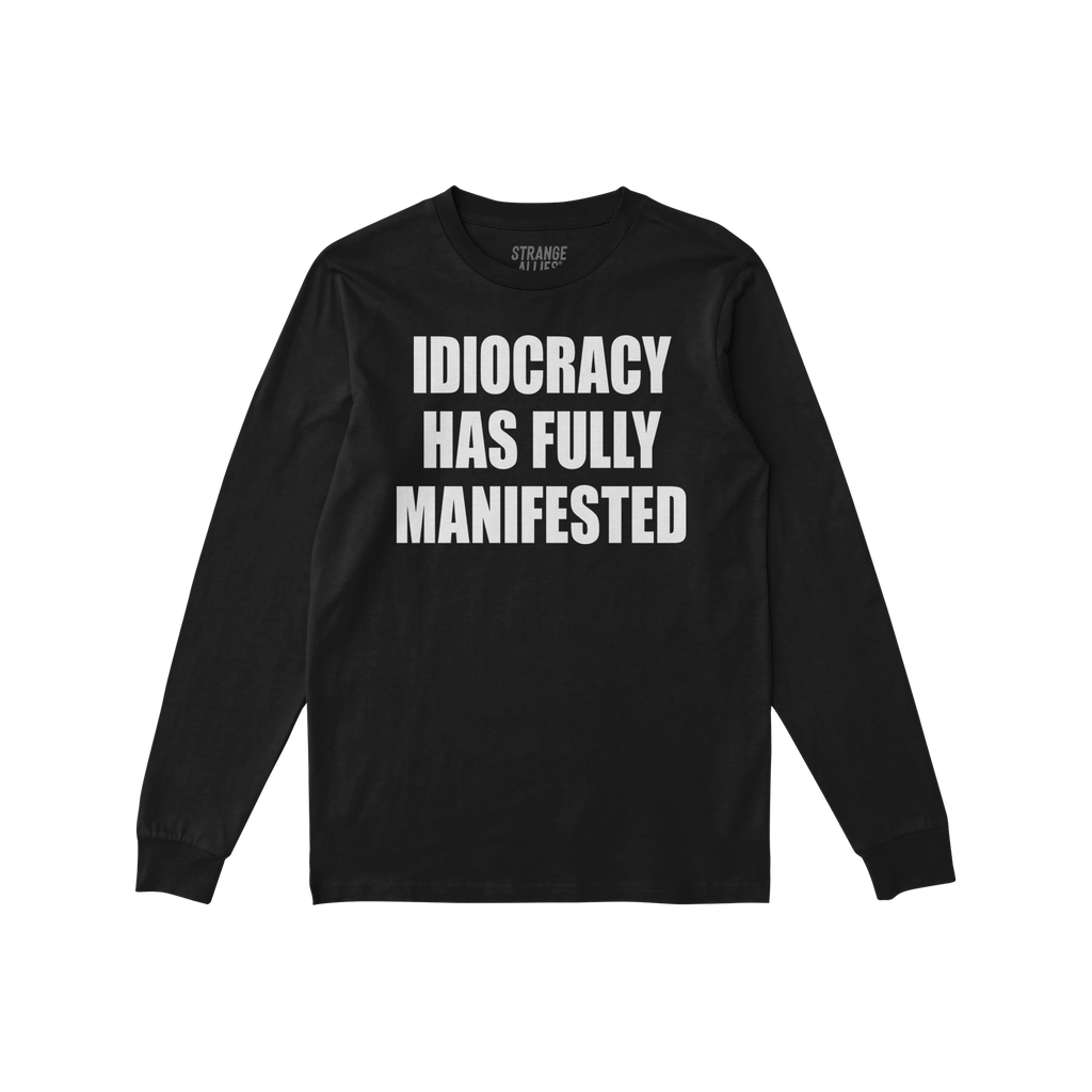 Black long-sleeve Idiocracy T-shirt features bold white text stating, IDIOCRACY HAS FULLY MANIFESTED, embodying a blunt socie