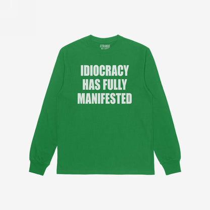 Green long-sleeve Idiocracy T-shirt features bold white lettering stating “IDIOCRACY HAS FULLY MANIFESTED. Ideal for those embracing political disillusionment with a touch of humor and truth.