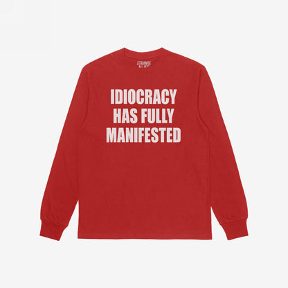Idiocracy T-shirt in red with bold white slogan IDIOCRACY HAS FULLY MANIFESTED on the front, reflecting a sharp, satirical message. Label inside the collar reads STRANGE ALLIES.