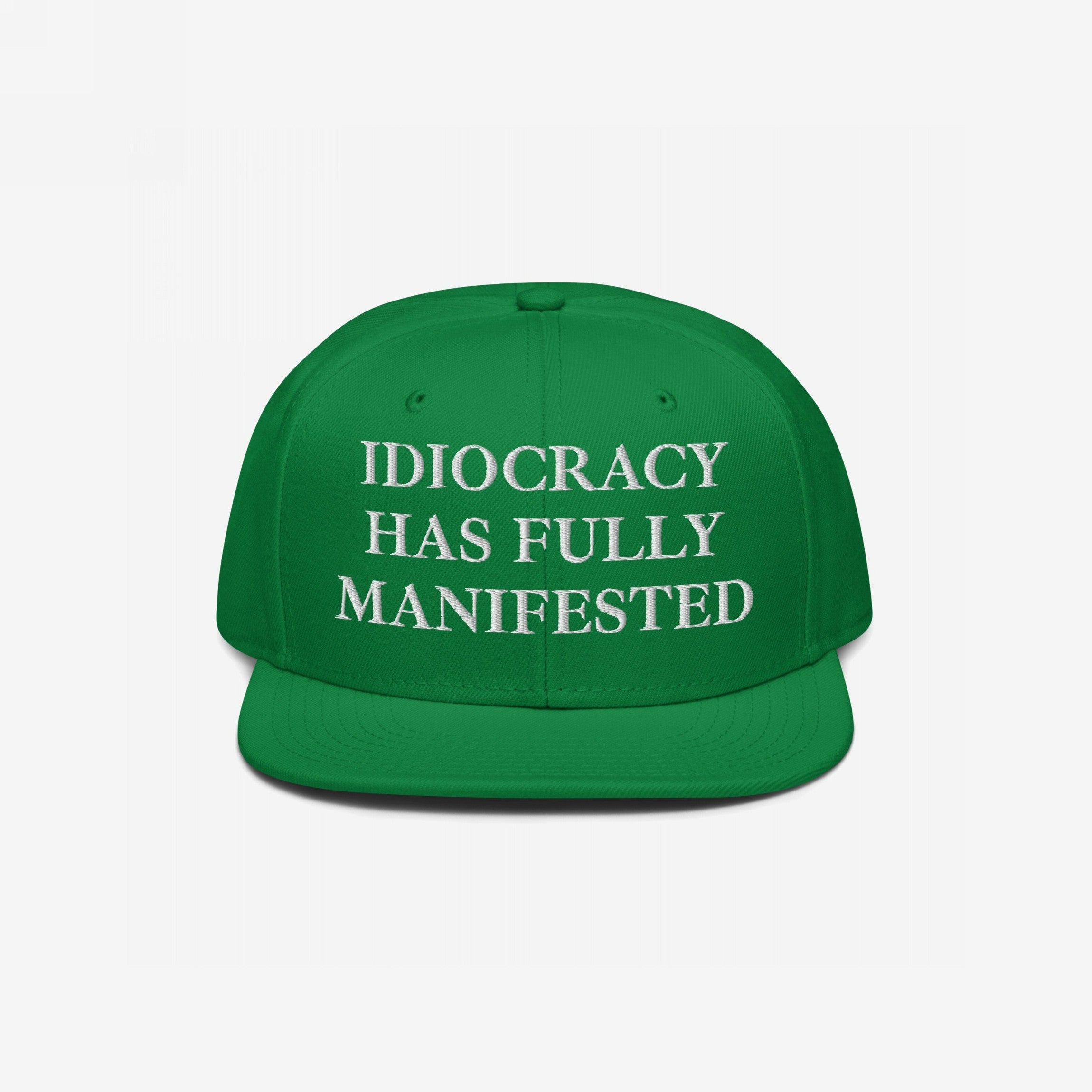 Green flat-brim cap with white embroidered text: “IDIOCRACY HAS FULLY MANIFESTED” in bold serif type, reflecting social commentary. The Idiocracy Hat embodies satire and truth for the observant wearer.