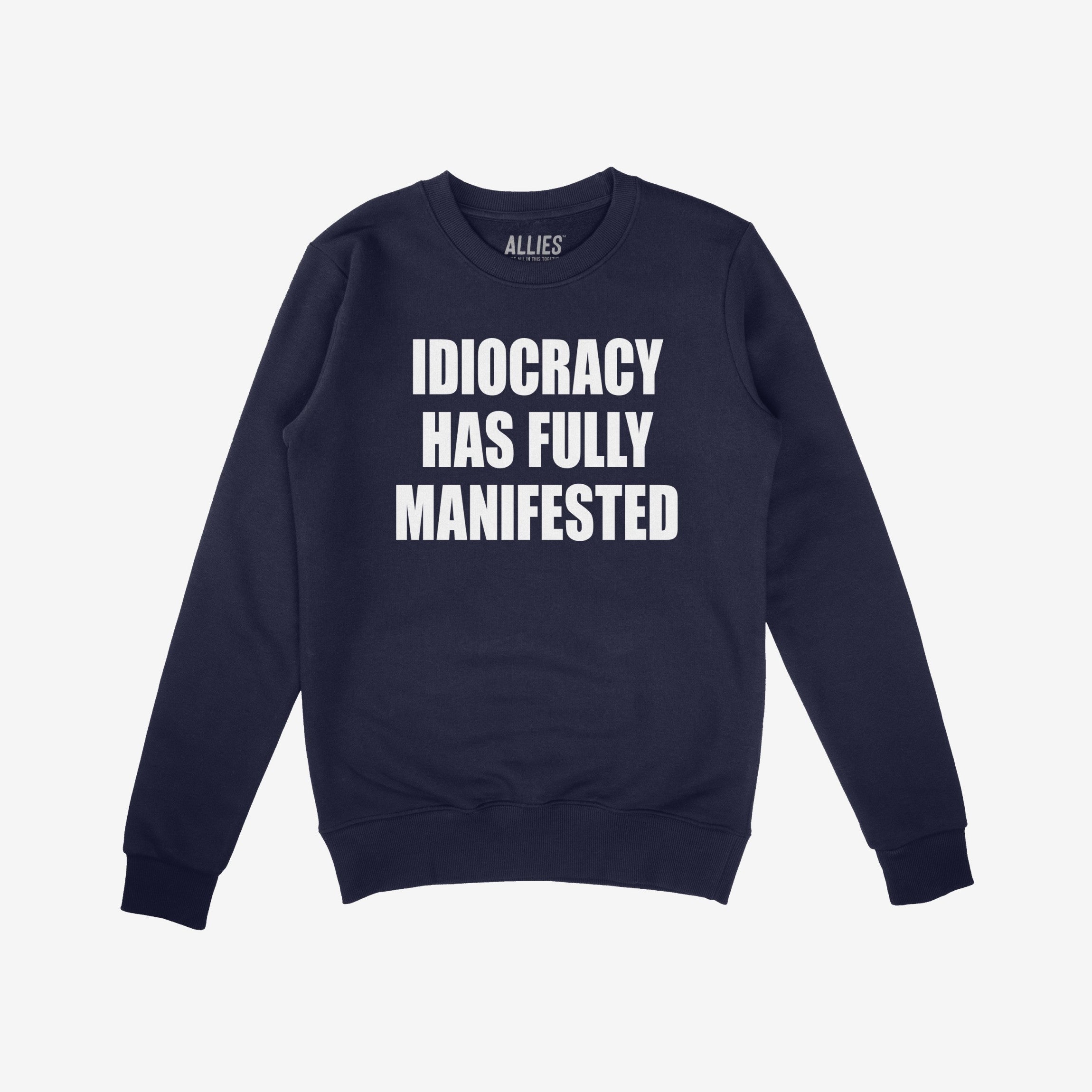 The Idiocracy Sweatshirt features bold white text declaring “IDIOCRACY HAS FULLY MANIFESTED” on a navy-blue crewneck, symbolizing protest against societal decline and stupidity in power.