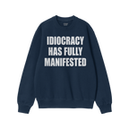 The Idiocracy Sweatshirt features bold white text declaring “IDIOCRACY HAS FULLY MANIFESTED” on a navy-blue crewneck, sym