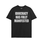 The Idiocracy T-shirt features bold white text stating “IDIOCRACY HAS FULLY MANIFESTED,” expressing a stark, satirical co