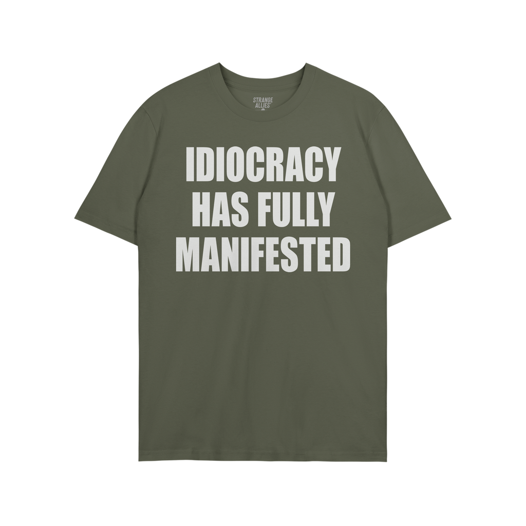 Green, short-sleeved Idiocracy T-shirt features bold white text stating “IDIOCRACY HAS FULLY MANIFESTED”, reflecting a sa