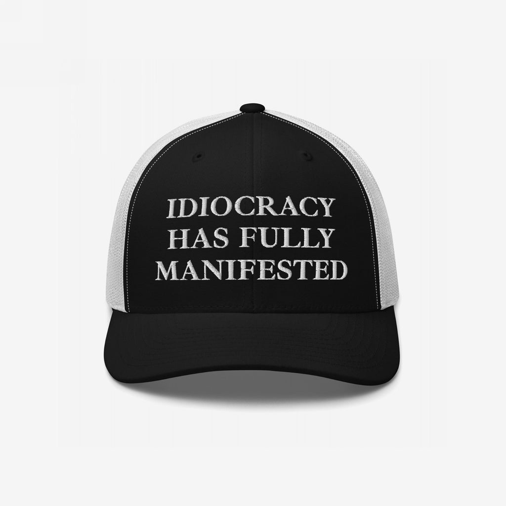 Black-and-white mesh trucker cap with IDIOCRACY HAS FULLY MANIFESTED embroidered in bold white serif letters on the front, reflecting satirical social commentary. Ideal for those embracing bold, thought-provoking fashion statements.
