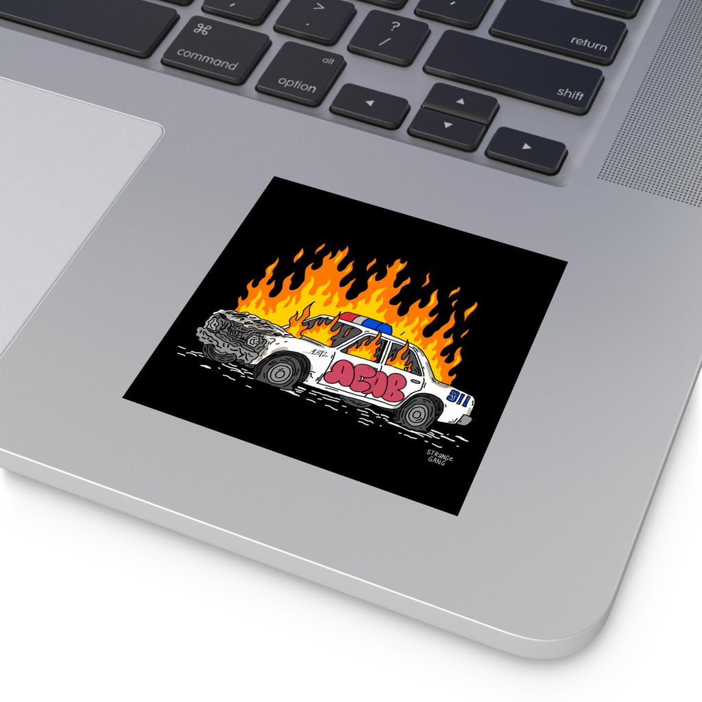 ACAB Police Car Sticker & Magnet on a laptop, featuring a cartoon-style burning police cruiser with 911 on the fender, crumpled front, and graffiti. Signature STRANGE GANG in corner.
