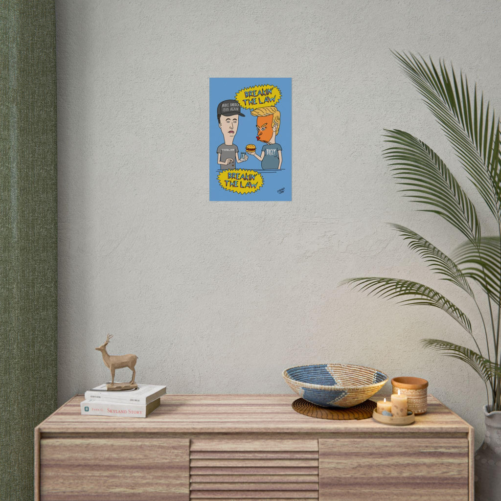 Breakin’ The Law Poster features a cartoon parody of Trump and Elon in a Beavis and Butt-Head style, criticizing MAGA and tech culture. Displayed above books and decor in a home setting.