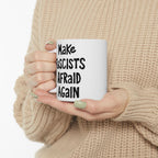 Person in chunky beige knit sweater holds the Make Fascists Afraid Again mug with bold, hand-drawn lettering, symbolizing resistance and activism, perfect for fueling determination in daily life.