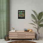 Don't Join A Cult Poster with fiery lettering on a light wall, above a wooden sideboard with books and a deer figurine, surrounded by decor like a woven basket and lit candles.