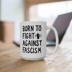 White ceramic Born to Fight Against Fascism mug with bold text and a raised fist graphic, set on a wooden tabletop, embodying progressive activism and everyday resistance.