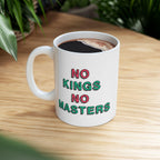 A white ceramic No Kings No Masters Mug on a wooden table, featuring a bold, hand-drawn slogan. It's filled with black coffee, embodying a rebellious spirit for those challenging authority.
