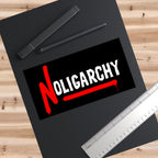The No Oligarchy Sticker & Magnet features bold white text disrupted by a red N, symbolizing resistance. It's set on a wooden surface with drawing tools nearby, embodying anti-authoritarian spirit.