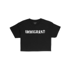Immigrant Women's Baby Tee featuring distressed white IMMIGRANT text with slash marks on black fabric, symbolizing strength a