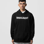 Young man in an Immigrant Hoodie & Sweatshirt with bold, distressed white IMMIGRANT lettering, symbolizing resistance and solidarity, ideal for protests and everyday activism, embodying support for immigrant communities.