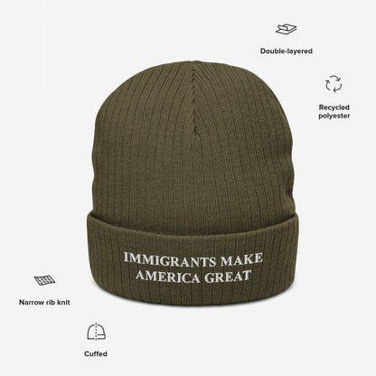Olive-green knit beanie with IMMIGRANTS MAKE AMERICA GREAT slogan embroidered on front, featuring narrow rib knit, cuffed style, and double-layered recycled polyester, embodying a bold statement for immigrant rights.