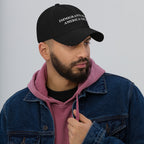 Young man wearing the Immigrants Make America Great Hat in black, embroidered in white, symbolizing solidarity and support for immigrant communities. His attire includes a hoodie and denim jacket, enhancing the hat's message.