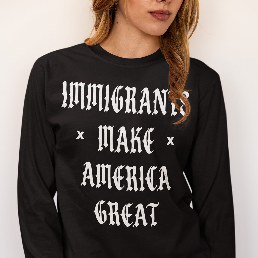 The Immigrants Make America Great Shirt features a bold statement in white Old English font on a black long-sleeve, advocating for dignity and justice, supporting equality and inclusion.