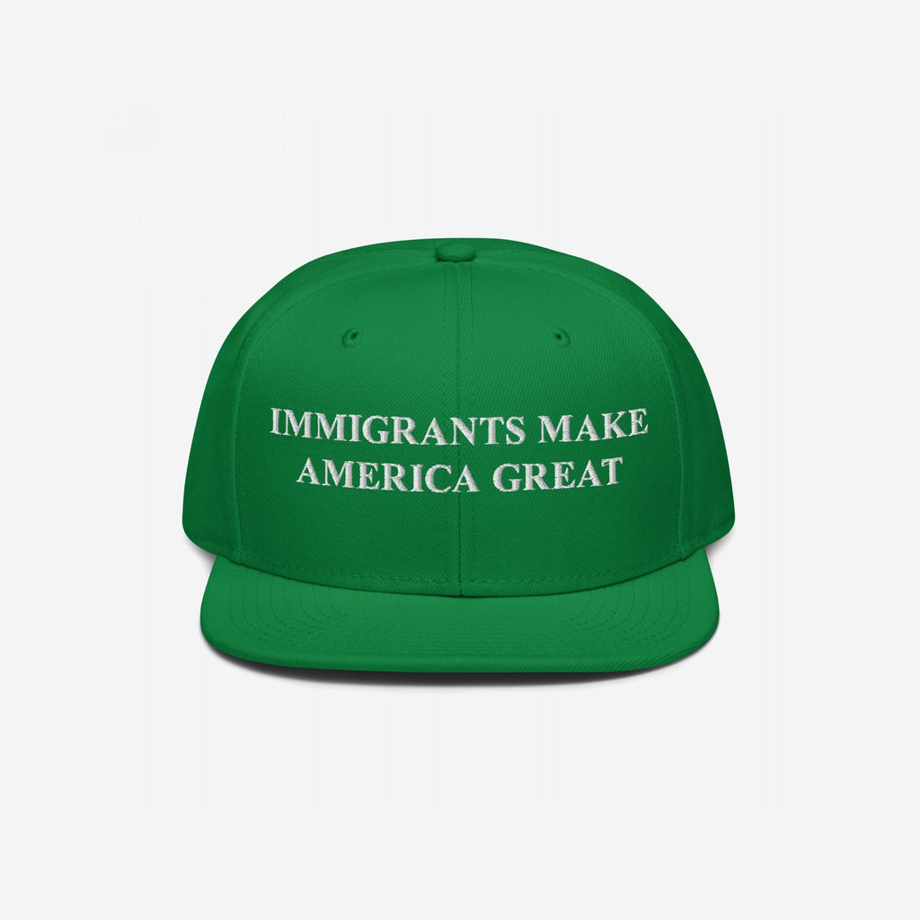 Immigrants Make America Great Hat: A green baseball cap with white embroidered text boldly proclaiming support for immigrant communities, emphasizing resilience and advocacy against hate and violence.
