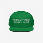 Immigrants Make America Great Hat: A green baseball cap with white embroidered text boldly proclaiming support for immigrant communities, emphasizing resilience and advocacy against hate and violence.