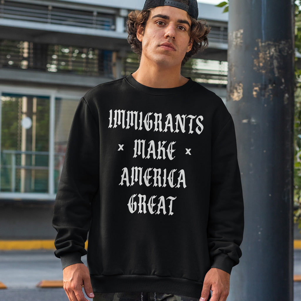 Young man wearing the Immigrants Make America Great Shirt, featuring bold, gothic-style lettering, stands outdoors. Paired with a black baseball cap and camo pants, the look embodies a protest-ready style.