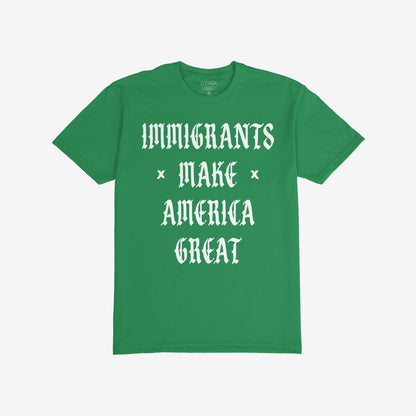 Immigrants Make America Great T-shirt featuring bold white Old English-style font, celebrates immigrant contributions and opposes xenophobia. The slogan is printed on the front of a plain green shirt.