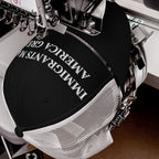 Immigrants Make America Great Hat in an embroidery machine, showcasing its bold slogan. This cap symbolizes solidarity and advocacy for immigrant communities, stitched for durability and impactful visibility.