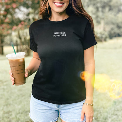 Intensive Purposes Women's Baby Tee features boldly on a smiling person outdoors, paired with denim shorts and a gold bracelet, capturing sunlight and chaos energy in its minimalist design.