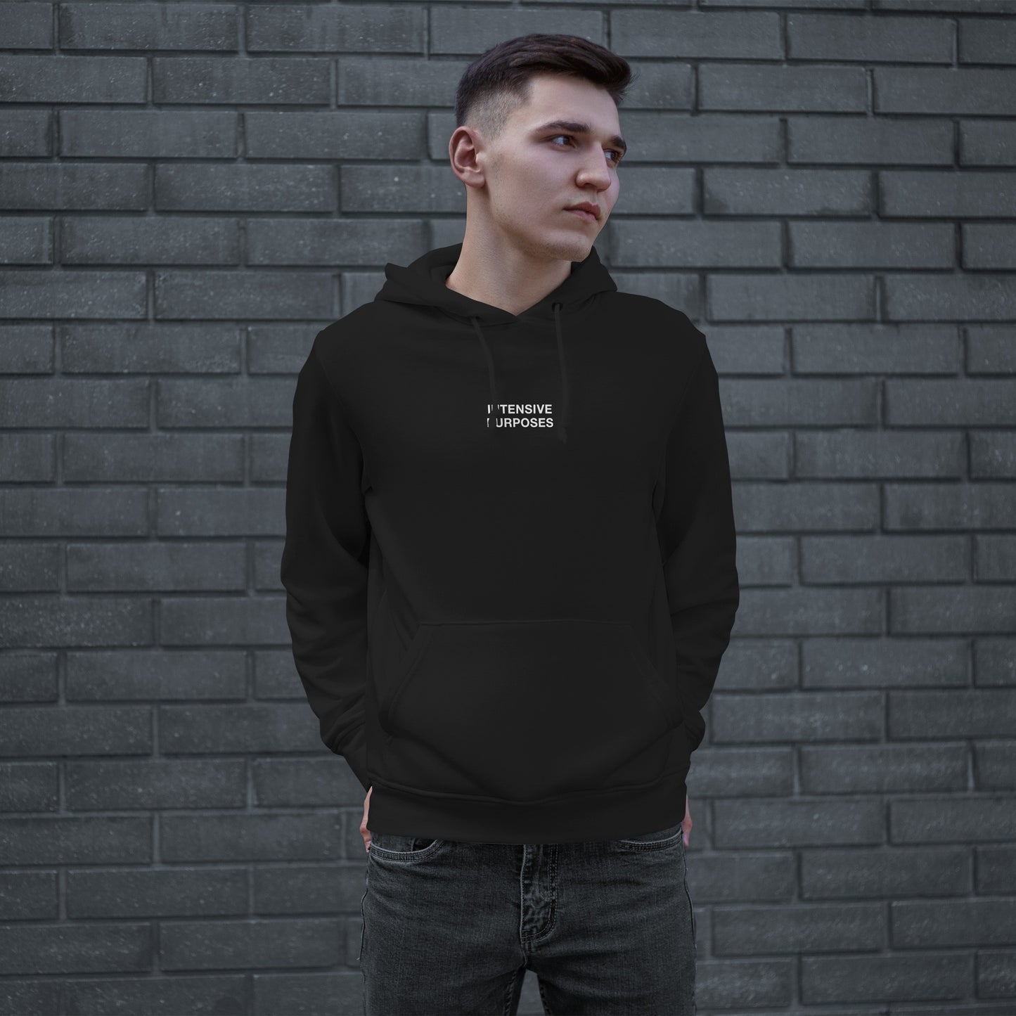 Young man in a black Intensive Purposes hoodie with white text, embodying street style and casual comfort. The hoodie is a nod to individuality and embracing imperfections.