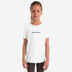 Young person in a white Irregardlessly T-shirt, featuring small black text, standing confidently with relaxed expression. Thin braids fall past shoulders. Perfect for fans of ironic humor and playful grammar.