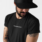 Bearded man in a black Irregardlessly T-shirt, tattoos visible, embodying ironic defiance.