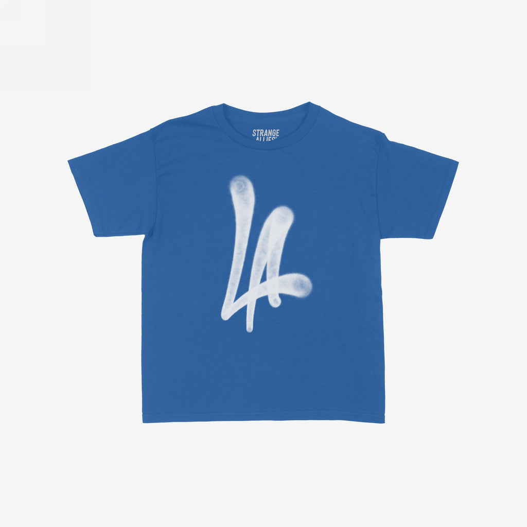 LA Handstyle Women's Baby Tee in medium blue features a bold white LA spray-paint graphic on the chest, capturing a retro Y2K vibe. The collar displays the tagline STRANGE ALLIES.